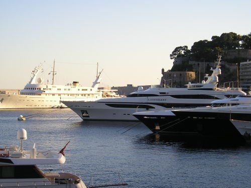 A row of boats are docked in a harbor and one of them has the word yacht on it