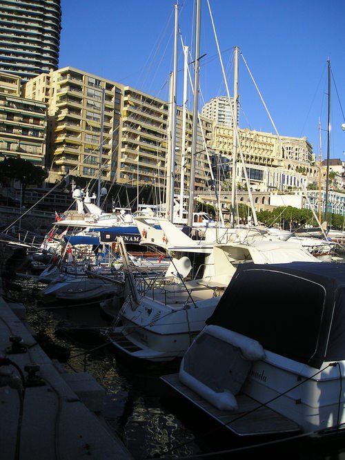 Several boats are docked in a harbor with buildings in the background
