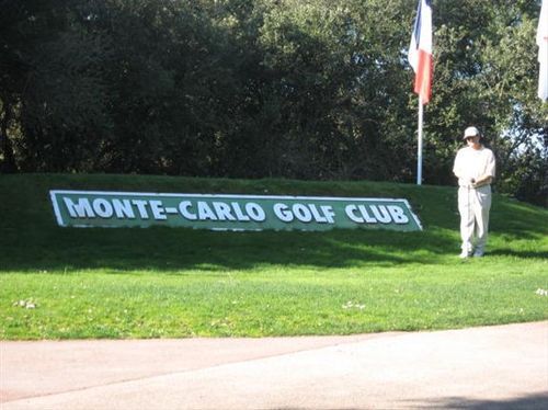 A man stands in front of a monte-carlo golf club sign