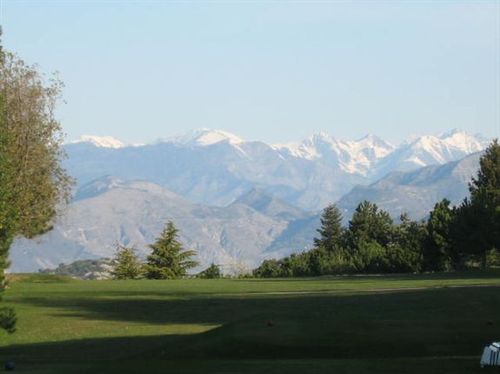A golf course with mountains in the background and trees in the foreground