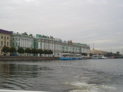 A large building is sitting on the shore of a body of water.
