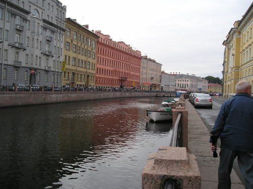 A man walking down a sidewalk next to a body of water