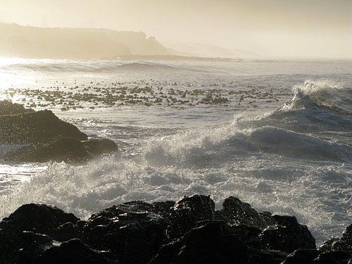 A large body of water with waves crashing on the rocks