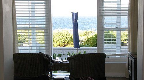 A living room with two chairs and a large window overlooking the ocean
