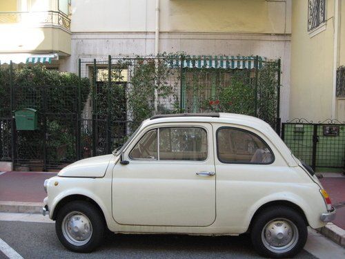 A small white car is parked in front of a building.