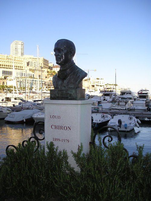 A statue of a man in a harbor with boats in the background.
