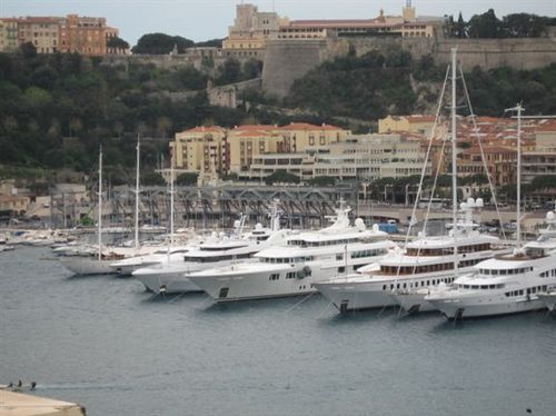 A row of boats are docked in a harbor with buildings in the background