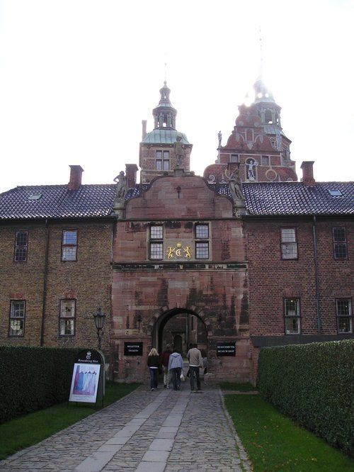 A group of people are walking towards a large brick building