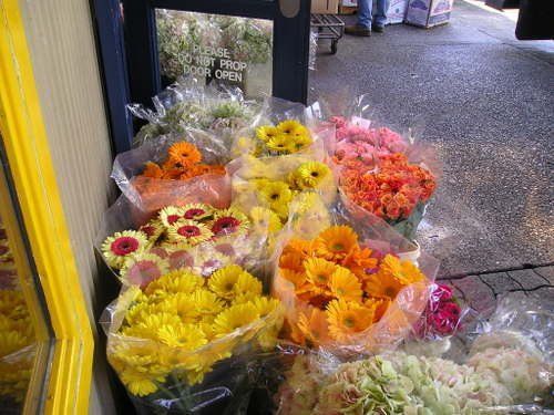 A bunch of flowers are sitting outside of a store