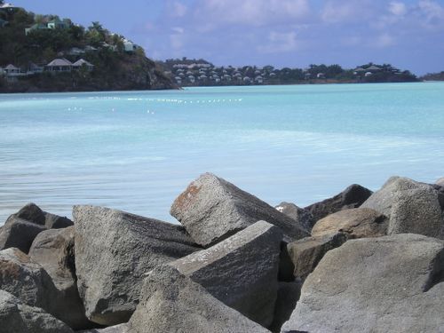 A pile of rocks on a beach with a body of water in the background