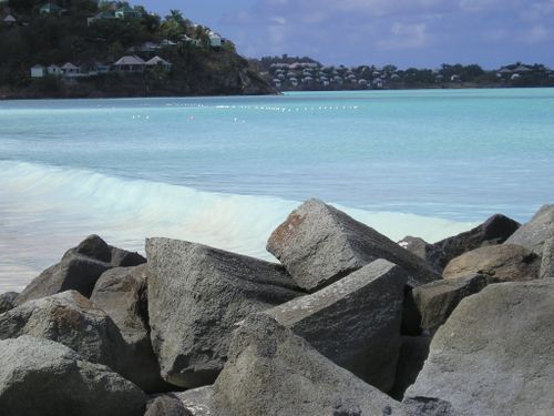 A beach with rocks in the foreground and a body of water in the background