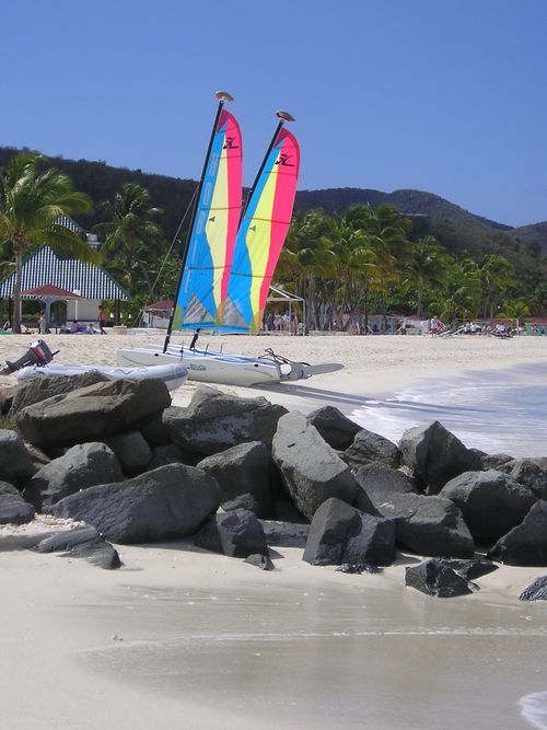 Two sailboats on a beach with mountains in the background