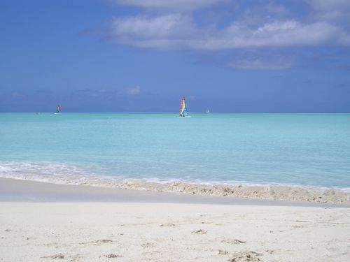 A white sandy beach with a sailboat in the distance