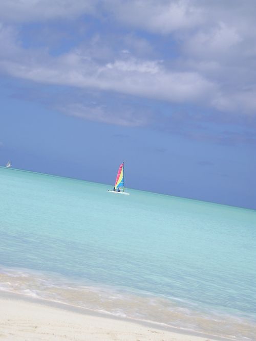 A sailboat is floating on top of a turquoise ocean.