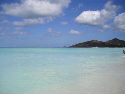 A beach with a boat in the water and mountains in the background