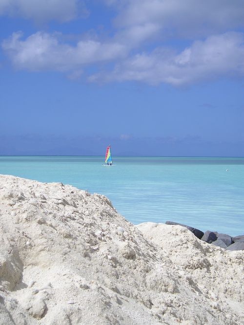 There is a sailboat in the distance on the beach.