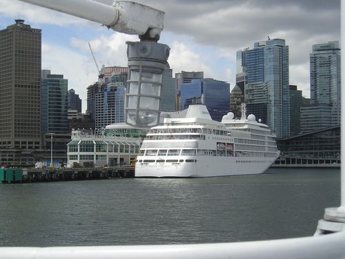 A large white cruise ship is docked in a harbor