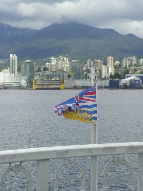 A flag is flying over a body of water with mountains in the background