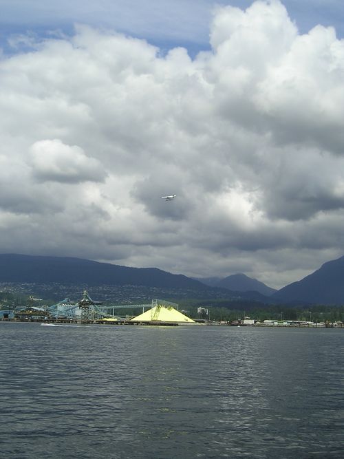 A plane is flying over a body of water with mountains in the background