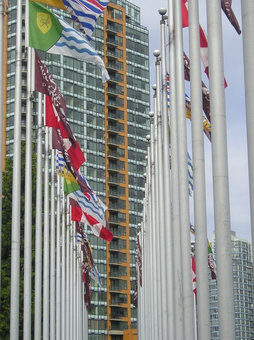 A row of flags are flying in front of a tall building