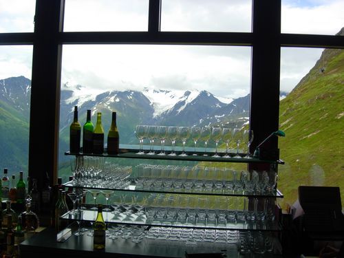 A bar with bottles and glasses and a view of mountains