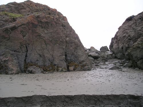 A rocky beach with a large rock in the middle of it