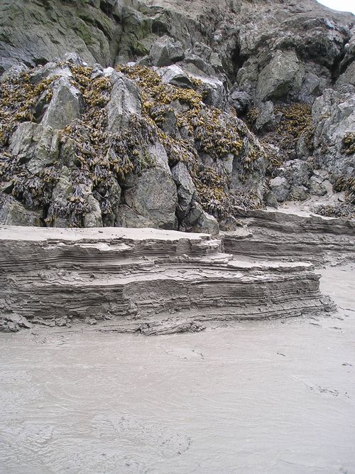 A pile of rocks sitting on top of a sandy beach.