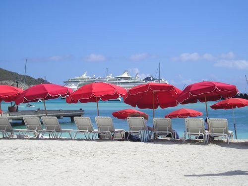 A row of red umbrellas and chairs on a beach