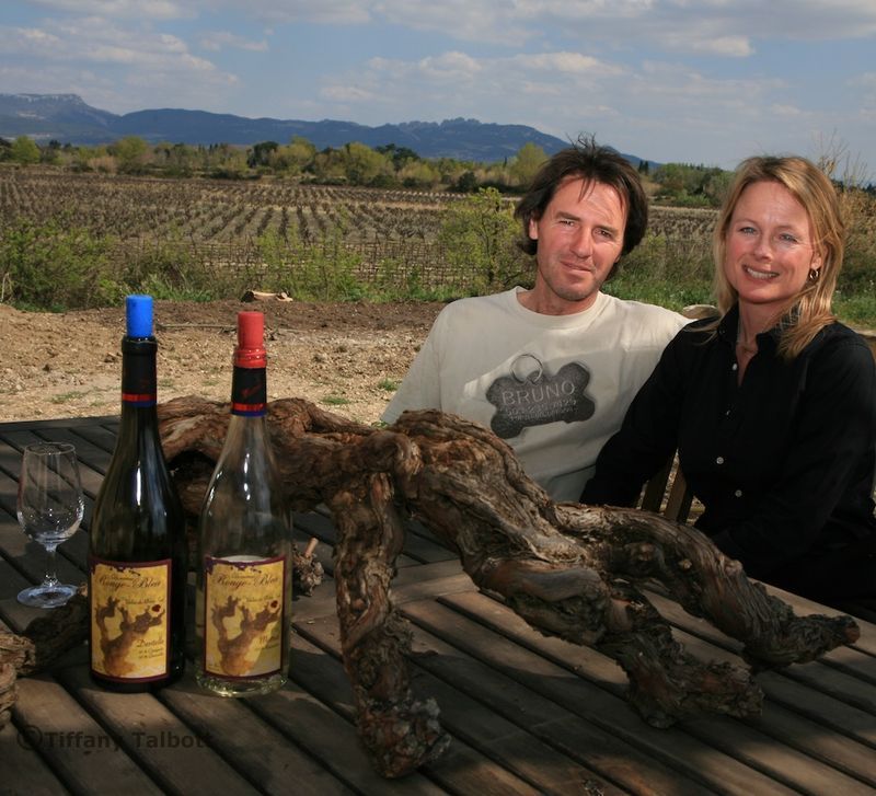 A man and a woman sit at a table with bottles of wine