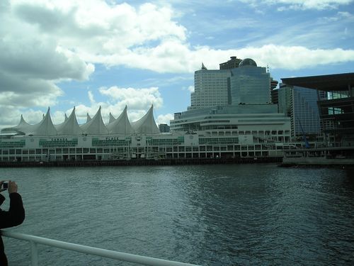 A person is taking a picture of a large building overlooking a body of water