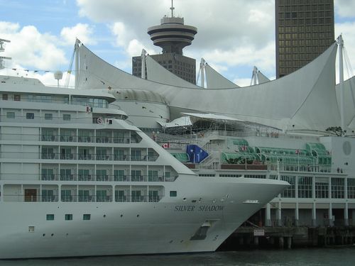 A large white cruise ship is docked in a harbor