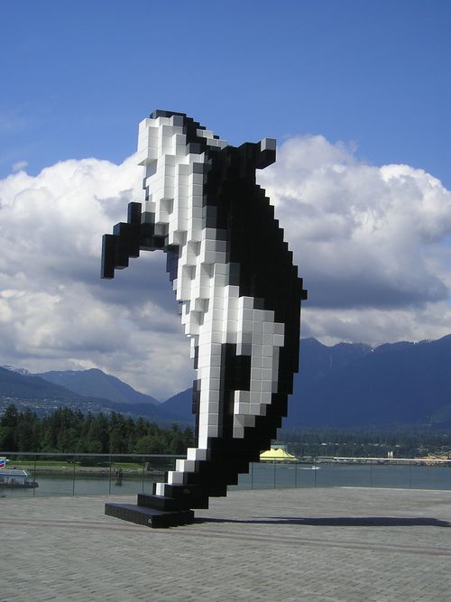 A black and white statue of a whale with mountains in the background