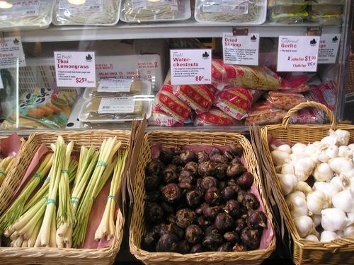 A display case filled with various vegetables including lemongrass and garlic