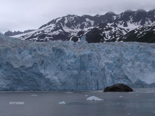 A large glacier in the middle of a lake with mountains in the background