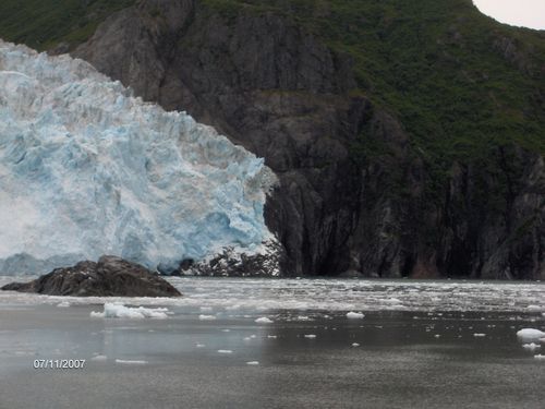A large glacier is surrounded by mountains and a body of water