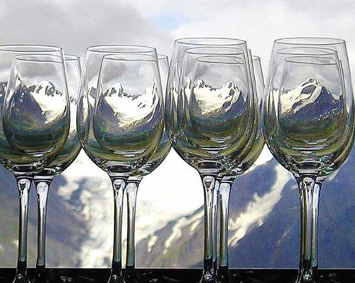A row of wine glasses with mountains reflected in them
