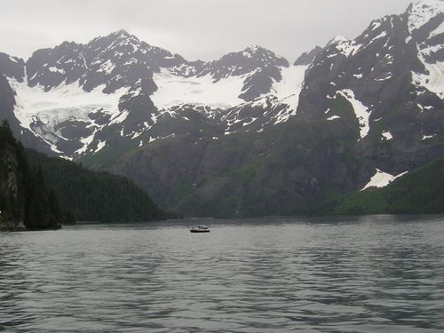 A boat is in the middle of a lake with mountains in the background