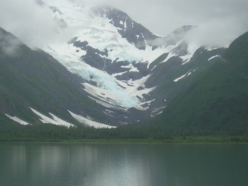 A mountain with snow on it and a lake in the foreground