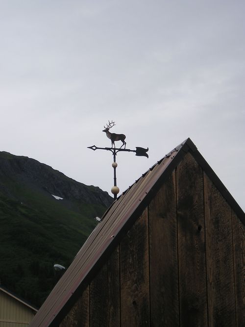 A weather vane with a deer on top of it