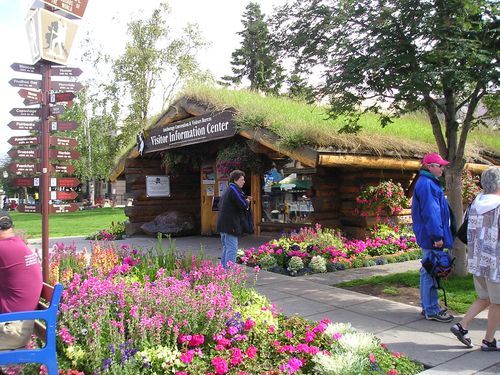 People walking in front of a building that says ' visitor information center ' on it