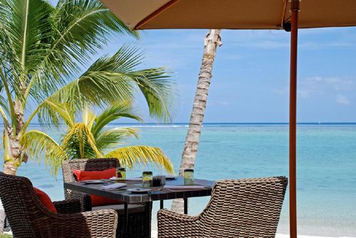 A table and chairs under an umbrella on the beach