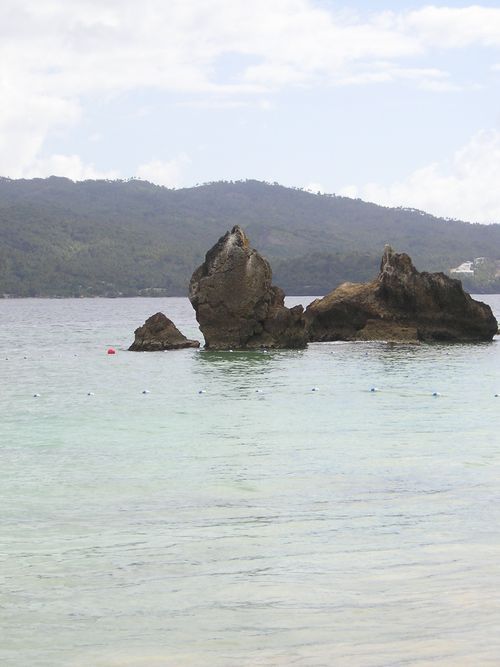A large rock in the middle of a body of water with mountains in the background.