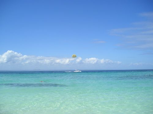 A person is parasailing over the ocean on a sunny day.