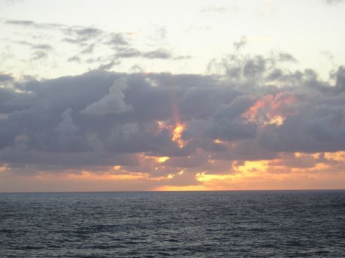 A sunset over the ocean with clouds in the sky