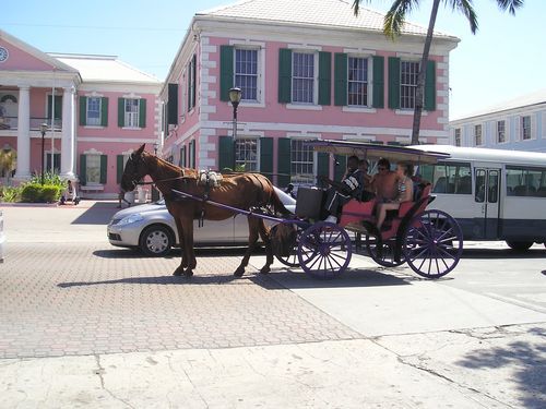 A horse drawn carriage is parked in front of a pink building