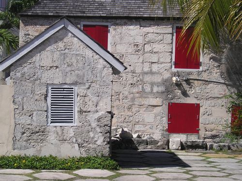 A stone building with red shutters on the windows