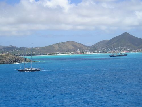 A boat is floating in the ocean with mountains in the background