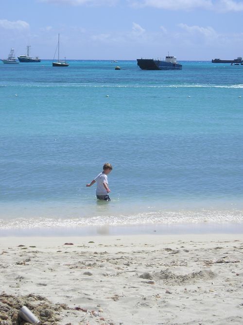 A man is walking out of the ocean on a beach