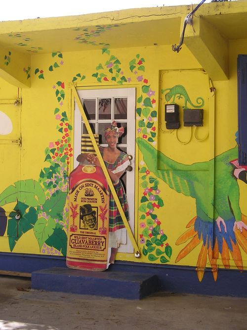 A yellow building with a painting of a woman and a bottle of tequila