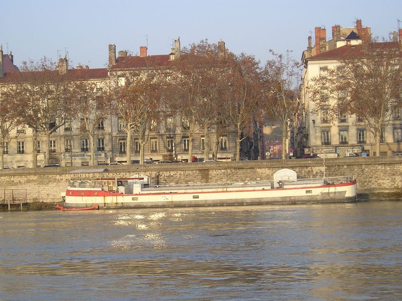 A boat is floating on a body of water with buildings in the background
